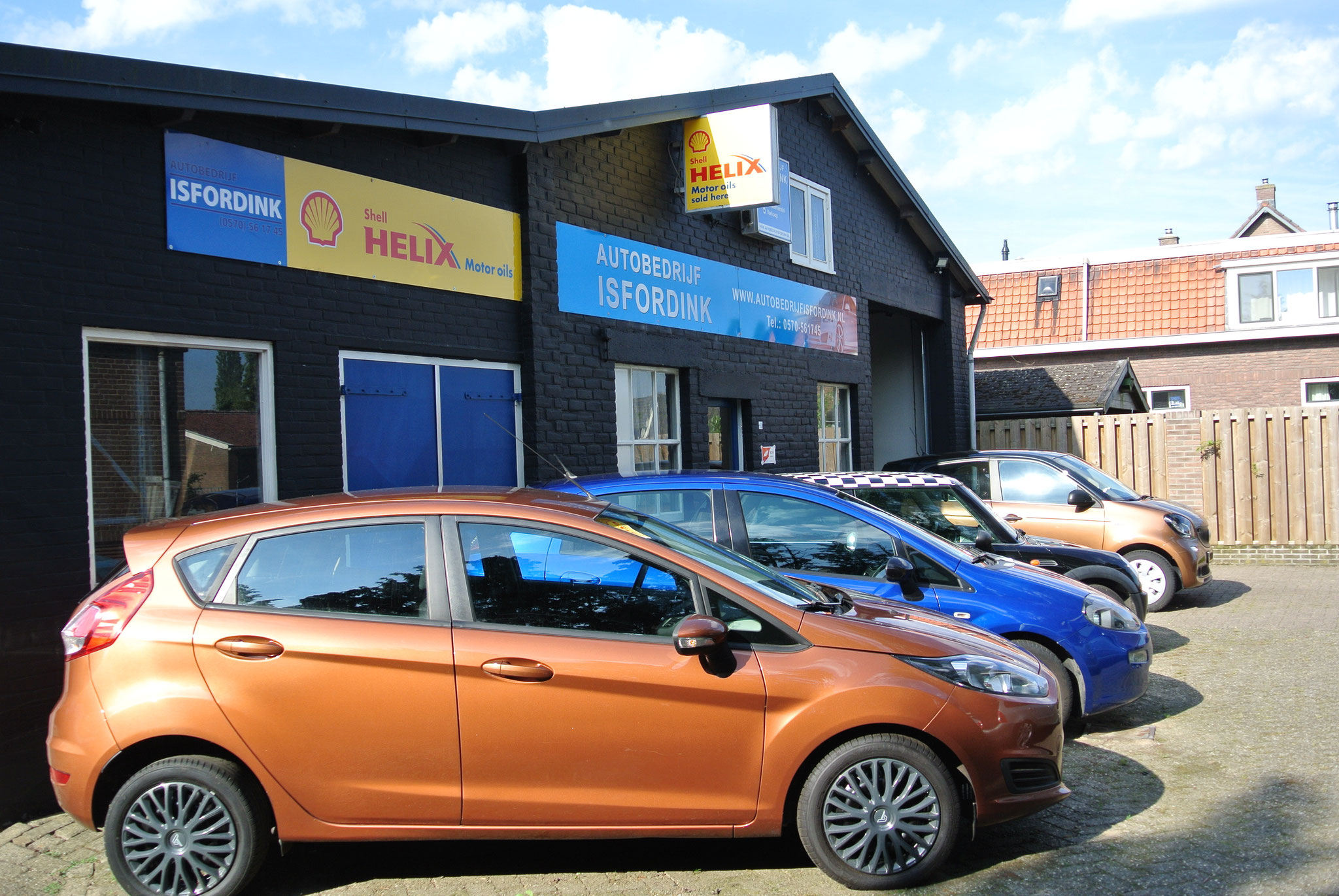 Een oranje Ford Fiesta voor het pand van Autobedrijf Isfordink