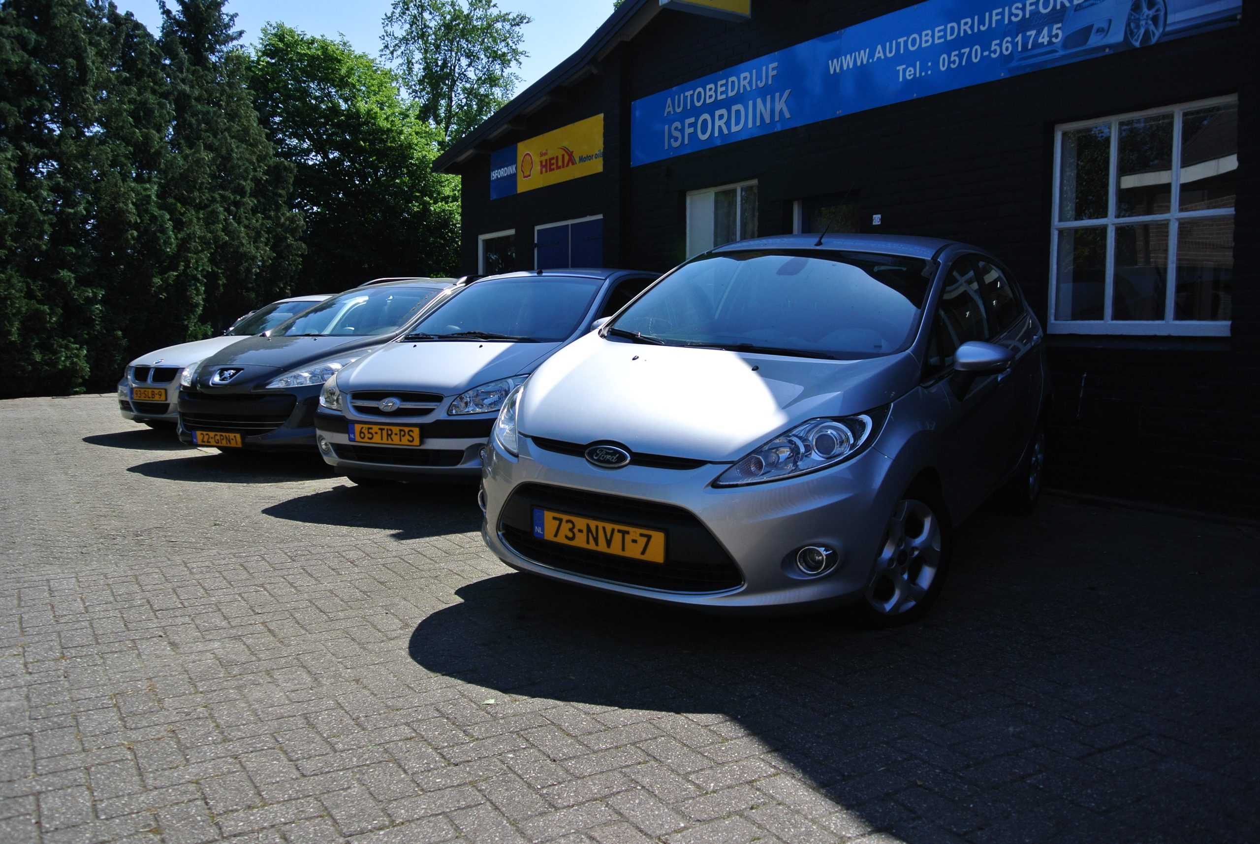 Het pand van Autobedrijf Isfordink aan de Boskamp met een rij auto's op de klinkers